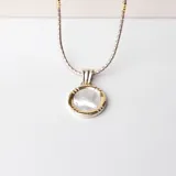 Conjunto de collar y dije circular en plata y oro con incrustación de nácar.