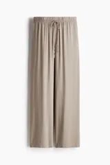Pantalón de viscosa color beige, de corte amplio, tiro alto, cintura elastizada con cordón de ajuste, bolsillos laterales y piernas rectas.