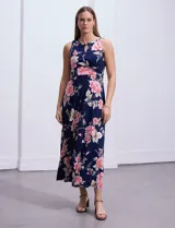Vestido largo de seda fría con estampado floral en tonos rosados y blancos sobre fondo azul marino. Presenta cuello redondo con abertura en forma de ojal y aplique metálico.