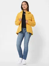 Campera amarilla acolchada con capucha, cierre frontal con cremallera, bolsillos laterales y logo de Tommy Hilfiger en el pecho.