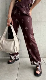 Pantalón marrón con estampado de rombos blancos y cintura elastizada.