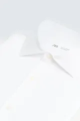 Camisa celeste a rayas verticales blancas, de corte recto, con cuello italiano abierto, manga larga con puños abotonados y cierre frontal con botones.
