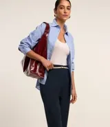 Pantalón de vestir azul marino, de corte zanahoria, con cinturón fino negro con hebilla dorada.