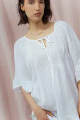 Vestido corto color beige de lino, con escote redondeado con lazo y mangas cortas amplias.