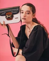 Bandolera color beige con textura símil reptil, cierre con broche metálico dorado y correa larga regulable.