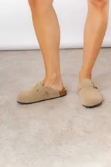 Zuecos de cuero color beige, con diseño clásico y hebilla regulable. Cuentan con plantilla anatómica y suela de corcho.