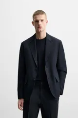 Blazer azul marino de corte recto, con cuello de solapa de muesca, cierre frontal con dos botones, bolsillos de solapa en la cadera y aberturas en la espalda. Confeccionado en tejido de algodón con elasticidad y sin forro interior.