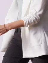 Blazer blanco de Robert Louis con cuello con solapa, abertura central con botón, bolsillos delanteros y mangas 3/4 con frunces.