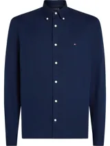 Camisa azul marino de corte slim, confeccionada en tejido dobby de algodón con Flex Technology, cuello abotonado, puños redondeados con dos botones y logo de Tommy Hilfiger bordado en el pecho.
