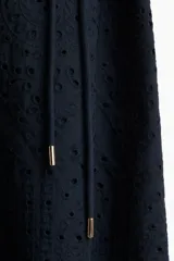 Vestido midi azul marino con broderie, cuello camisero, botones ocultos, mangas abullonadas al codo, cinturón fino con borlas y ribete festoneado en puños y bajo.