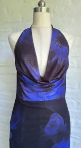 Vestido largo de fiesta con estampado floral en tonos azul y negro, escote halter y espalda descubierta.