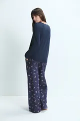 Pijama de dos piezas confeccionado en mezcla de bambú y algodón. Incluye una remera de manga larga lisa en color azul marino con un pequeño detalle bordado de corazones en el pecho y un pantalón largo con estampado floral y cintura elástica.