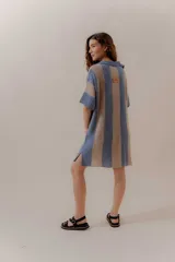 Vestido corto tejido a rayas verticales color crudo y rojo, con cuello polo abierto y mangas cortas. Confeccionado en Uruguay con 50% poliéster y 50% algodón.