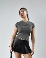 Remera gris de tejido de punto acanalado, con cuello redondo, mangas cortas con detalle desflecado y bajo con roturas.