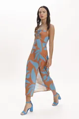 Vestido midi con estampado floral en tonos beige y negro, con escote halter, abertura en el abdomen y falda recta con tajo lateral.