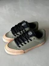Championes CIRCA BUCKLER 99 de skate color verde oliva con puntera y suela color durazno, cordones negros y logo en la lengüeta.