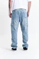 Pantalón cargo color beige, de corte recto, con bolsillos laterales y traseros. Se ajusta a la cintura con cinturón de cuero marrón.