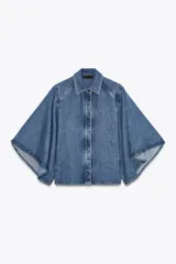 Camisa de denim azul con cuello solapa y mangas amplias tipo kimono. Tiene efecto lavado y cierre frontal con botones ocultos.