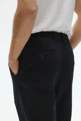 Pantalón negro de corte slim fit, confeccionado en sarga elástica de algodón. Cuenta con cierre y botón, bolsillos al bies y bolsillos insertados atrás con botón.