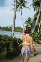 Pareo rectangular con estampado a cuadros en tonos celeste, naranja y blanco, con detalle de flecos en los bordes.