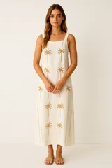 Vestido largo color crudo con estampado de palmeras doradas, corte recto y breteles anchos.