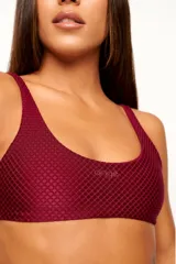 Top deportivo reversible color bordó, con diseño slim, tirantes finos y espalda descubierta. Un lado tiene acabado brillante y el otro textura 3D tipo colmena.