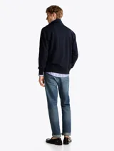 Buzo azul marino de felpa de algodón con cuello chimenea, cierre de cremallera, dos bolsillos delanteros estilo canguro, puños y bajo de punto canalé, logo de Tommy Hilfiger bordado en el pecho y detalles distintivos de la marca.