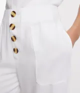 Pantalón blanco acampanado de viscosa con cintura mediana, cierre con botones y bolsillos laterales.