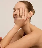 Set de 6 anillos dorados de diferentes diseños: uno con colgante de estrella, uno con forma de flor alambrada, uno con una piedra brillante, uno liso, uno trenzado y uno torcido.