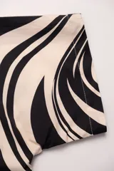 Camisa de manga corta con cuello tipo camp, con estampado abstracto en tonos beige y negro.