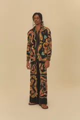 Pantalón de corte amplio con estampado de cachemir en tonos naranja, marrón y celeste sobre fondo negro. Presenta cintura elástica con cordón ajustable.