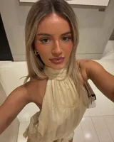 Minivestido color crema con cuello halter, espalda descubierta y falda con volados.