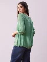 Blusa verde agua de gasa con cuello redondo y aplique de crochet. Tiene mangas 3/4 amplias con puño y botón, y forro interno a tono.