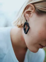 Aros colgantes con forma geométrica irregular, hechos a mano en cristal de murano negro y aro de acero quirúrgico plateado.