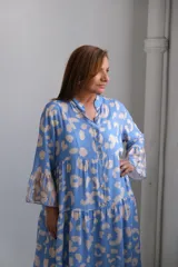 Vestido midi celeste con estampado de manchas beige, cuello mao, mangas 3/4 acampanadas y corte escalonado.