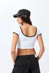 Top corto de punto acanalado color rosa, con silueta ajustada, escote redondo y ribetes blancos en cuello y mangas.