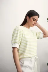 Remera de manga corta con cuello redondo y estampado de rayas horizontales blancas y negras. Mangas abullonadas con puño blanco.