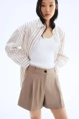 Short color beige de corte sastrero, con cierre y botón, bolsillos al bies y bolsillo trasero decorativo. Piernas con pinzas y pliegues adelante y atrás.