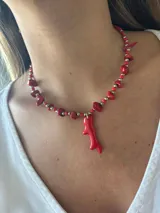 Collar de diseño artístico con cuentas rojas y detalle en forma de figura, ajustable en la parte posterior.