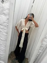 Top de lino color crudo con mangas amplias y lazo versátil para atar al frente o cruzarlo y ajustarlo atrás.