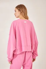 Buzo rosa con cuello redondo y estampado de flores blancas formando un corazón en el frente.