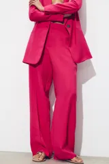 Pantalón de tiro alto color fucsia, con bolsillos delanteros y falsos bolsillos de vivo en la espalda. Tejido con efecto arrugado, pernera recta y cierre frontal con cremallera, botón interior y gancho.