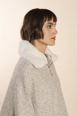 Poncho color crema con cuello de corderito desmontable y cierre dorado.