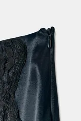 Minifalda azul petróleo de satén con encaje negro en el frente, corte al bies y cierre lateral invisible.