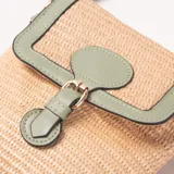 Cartera bandolera de rafia color beige con detalles en verde menta. Tiene una solapa con cierre de broche y correa ajustable.
