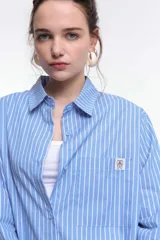 Camisa a rayas verticales rojas y blancas, de corte recto, con cuello clásico, manga larga y bolsillo en el pecho.