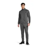 Conjunto deportivo Under Armour gris con detalles en negro. Incluye campera con cierre y pantalón con cintura elástica y cordón ajustable. Ambos con logo de la marca en el pecho y en la pierna.