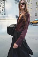 Falda midi negra de tiro medio confeccionada en hilatura con lana. Diseño con tablas y cierre con cremallera oculta en costura.