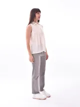Camisa sin mangas color crudo con cuello clásico, cierre frontal con botones y diseño calado vertical.