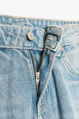 Pantalón de jean celeste claro, de tiro bajo, corte wide leg y largo hasta el tobillo. Tiene cinco bolsillos, cierre frontal con cremallera y botón metálico.